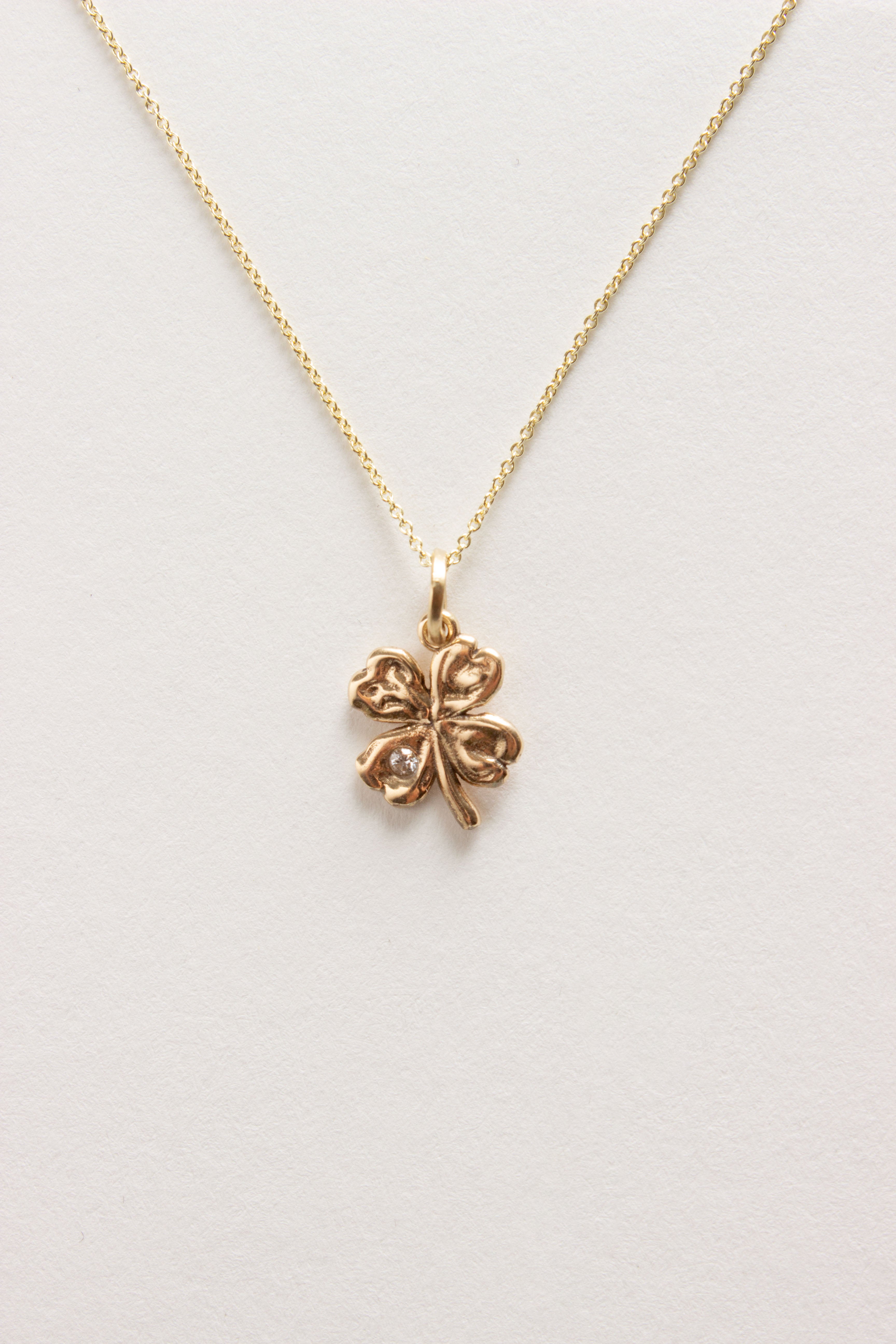 Gold four leaf amulet necklace on gold chain with one diamond